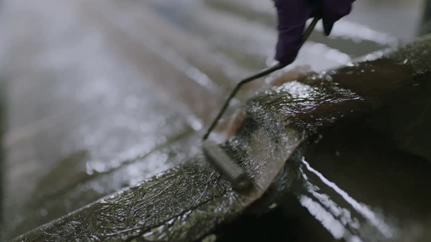 A person applies adhesive with a roller