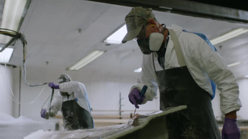 Two people in protective clothing in an indoor space carrying out cleaning