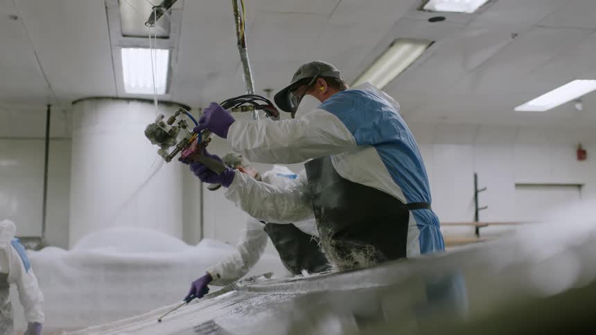 Four employees wearing safety gear work in a factory