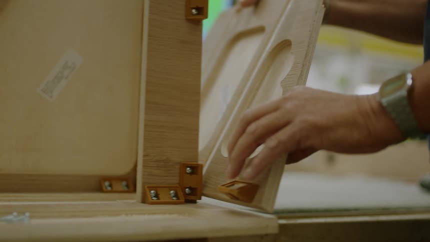 Persons hand gluing a wooden sheet to a surface on the table