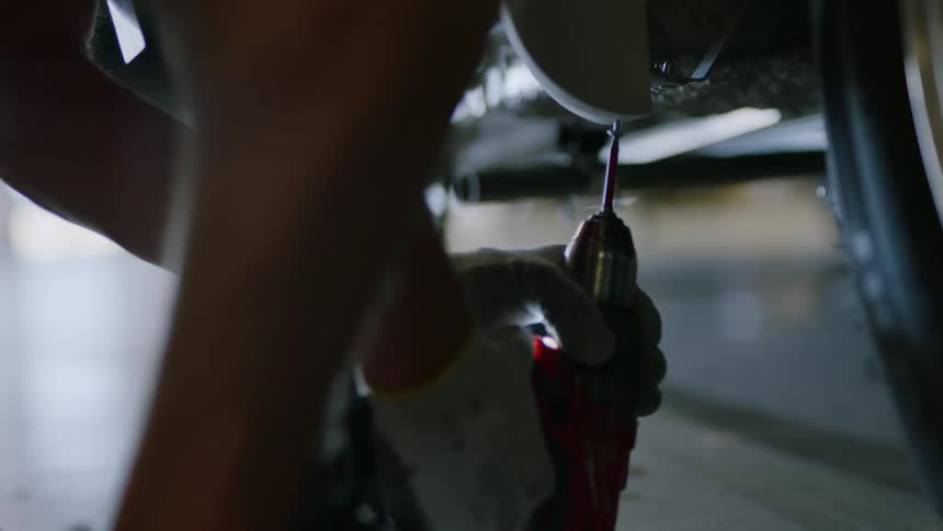 Human hands that are with gloves are screwing a screw into a metal object