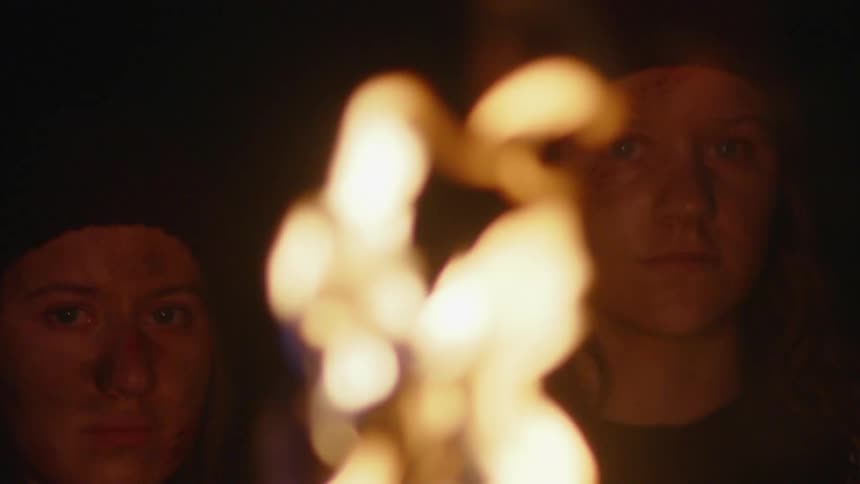Torch with lit fire and in the background portrait of two young women