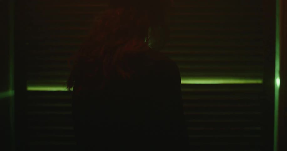 Silhouette of a woman next to a curtain in a dark room with natural lights