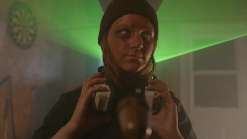 Woman with a fearful facial expression taking off her headphones and a green detection light passing close to her body