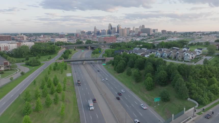 Aerial of suburbs and a highway outside of a metropolis on a summer day