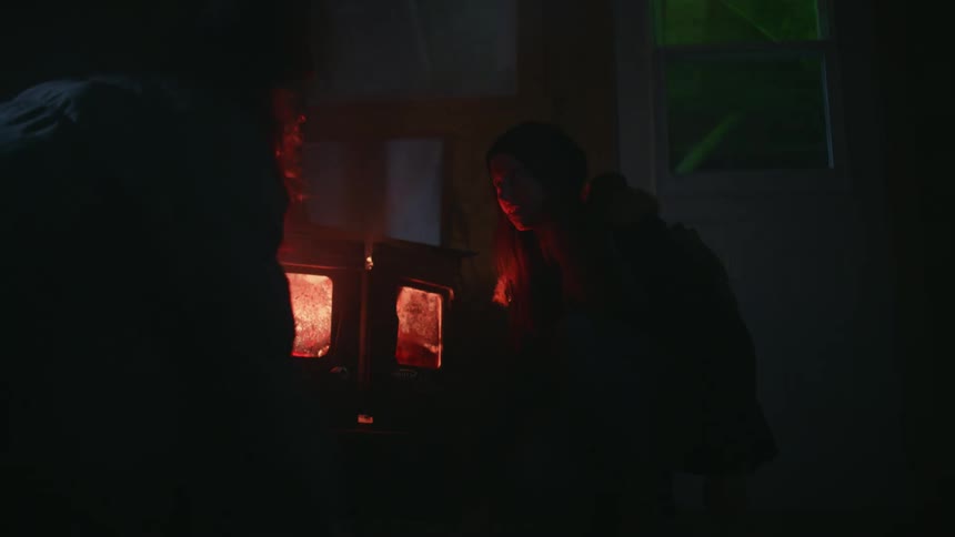 Two women run into a house and hide from a green laser scanning for them through a window