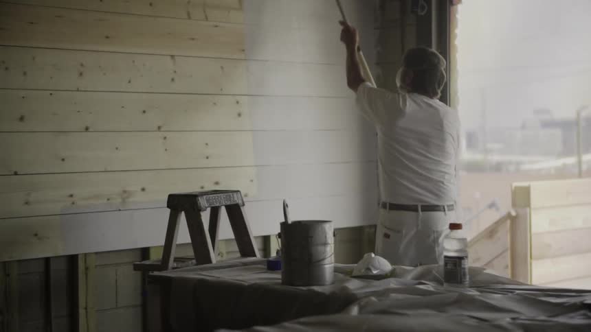 A man painting inside a building on a cloudy day