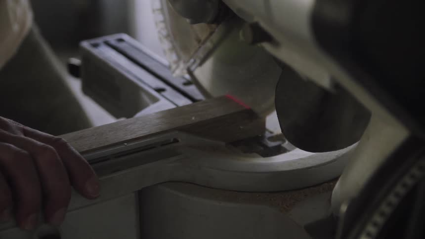 Person using miter saw to cut a piece off of block of wood
