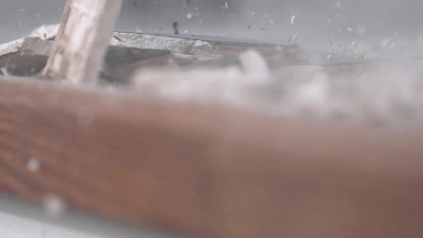 A sledgehammer smashing tile and sending it flying into the air