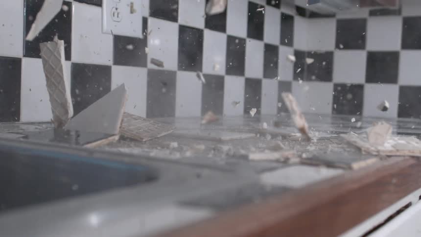 Extremely slow-motion scene of ceramic tiles being destroyed by a large hammer