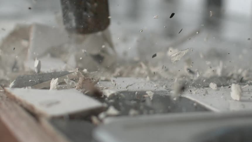 A sledgehammer smashes and shatters tiles