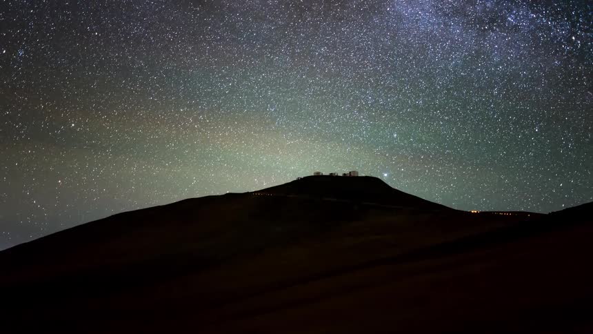A night sky filled with stars over a silhouette of a hill or mountain range transitions to daytime
