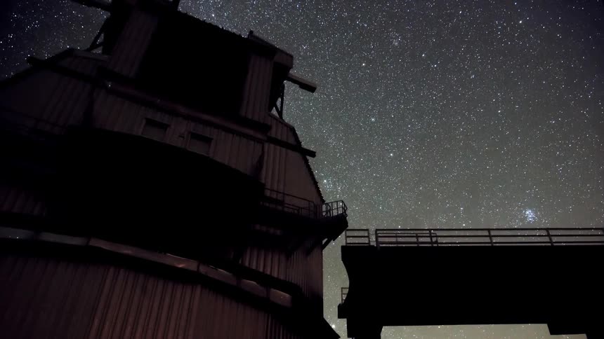 Large metallic observatory in motion against a sky with stars at night