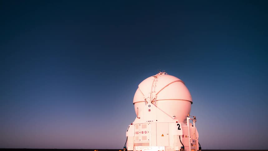 Night turns to dawn with the sun lighting up an observatory