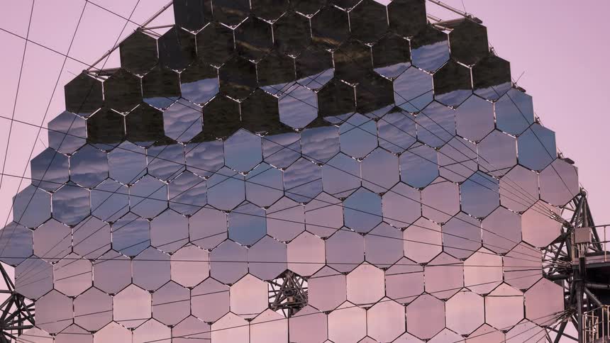 Complex geometric structure composed of multiple hexagonal panels that reflect the sky in different tones
