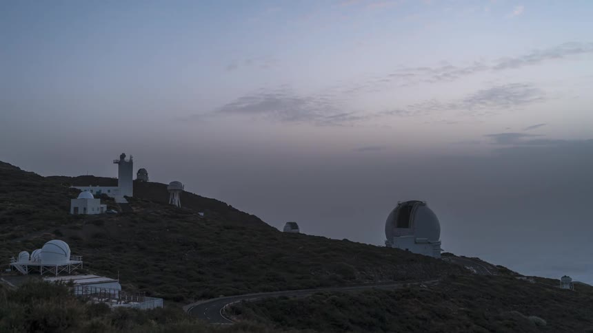 Antennas and observatories on mountain peaks against a darkening sky