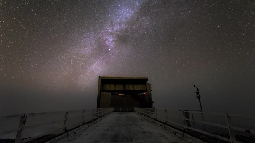 Night view of a starry sky with the milky way visible above an observatory structure
