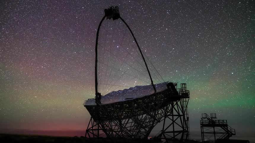 Large radio telescope at night with its metallic structure and antenna against a starry sky that displays shades of purple and green