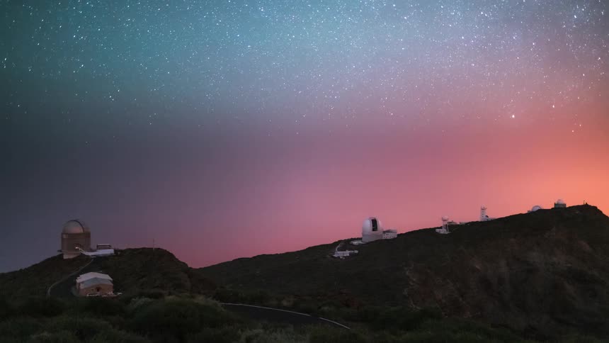The milky way twists in the sky over several observatories