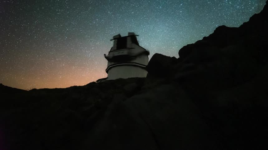 Observatory in the silhouette of a mountain against a starry sky