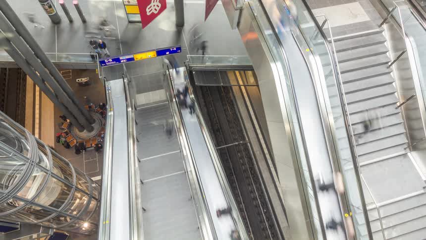 Modern interior of a building with escalators and thousands of people passing by