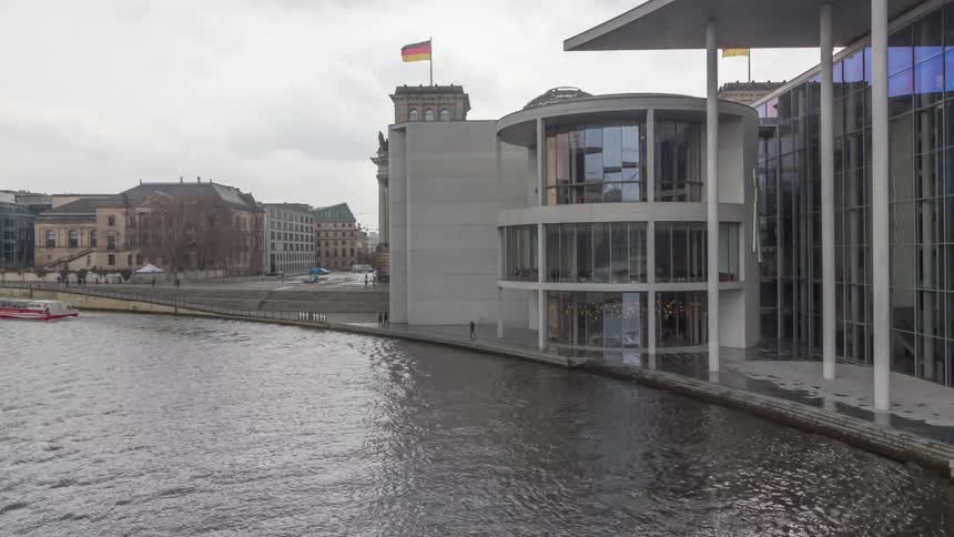 View of the river spree in berlin highlighting the glass dome of the reichstag and the citys modern architecture under a cloudy sky