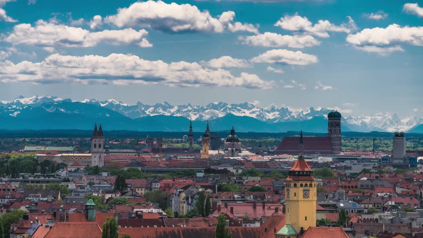 A small town with some towers and in the background there is a range of mountains that complicate the snow cover