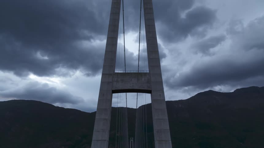 Large bridge that crosses the sea giving access to a mountain against a cloudy sky