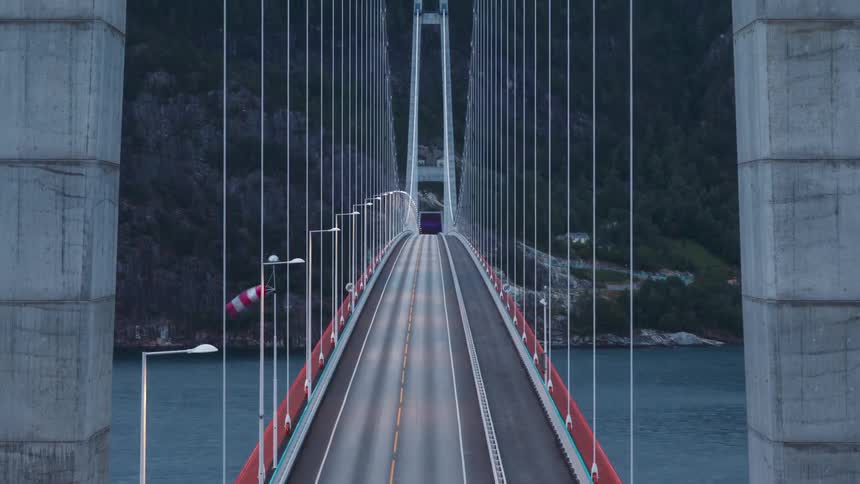 Suspension bridge with steel cables above the sea and cars passing by