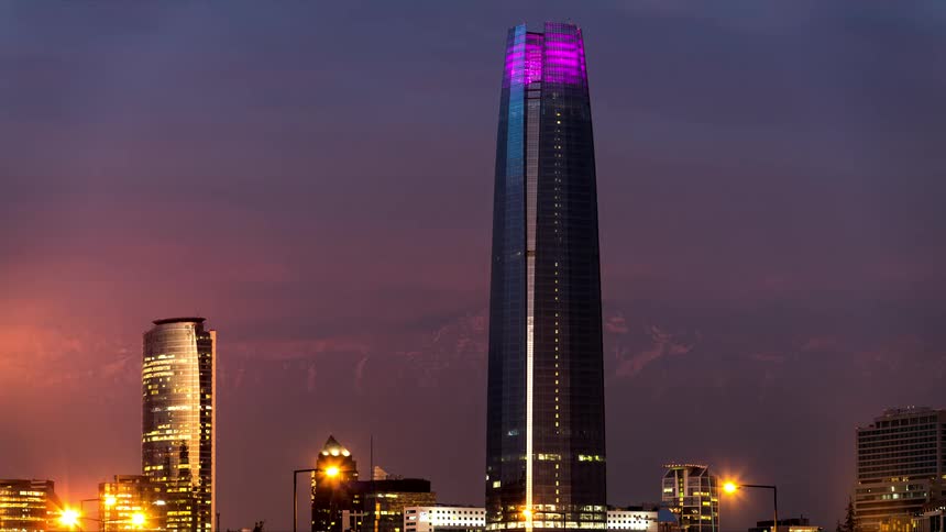 A large commercial building topped with a purple light on a sunset