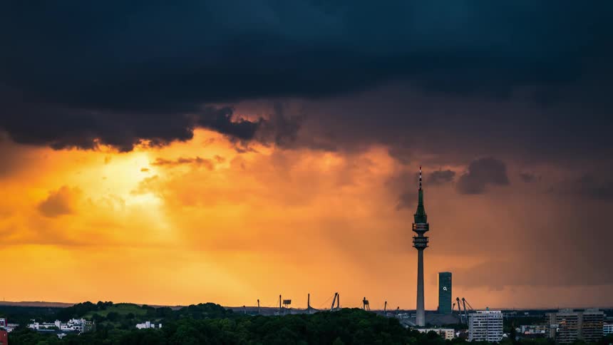 Cityscape with a dramatic sky where dark stormy clouds rain above a communications tower