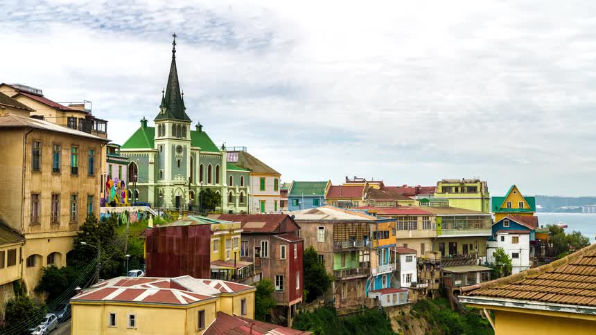 A crowd of people visit a church in a colorful coastal suburb