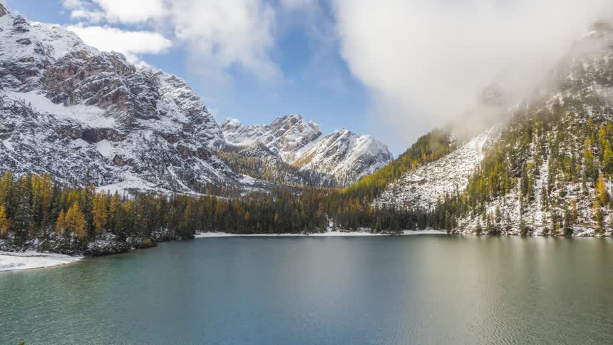 A snow covered mountain range landscape featuring a serene mountain lake
