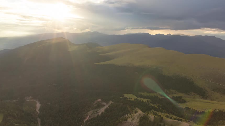 Landscape of greenish mountains in a cloudy sky with reflections of natural sunlight