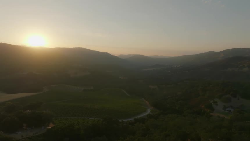 Sun rises over mountains onto fields of crops