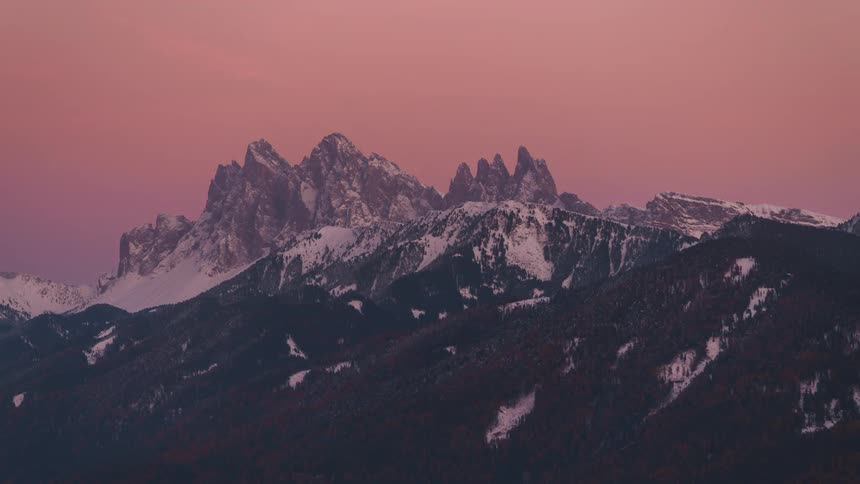 Landscape of a mountainous valley with snowcapped peaks and dusk