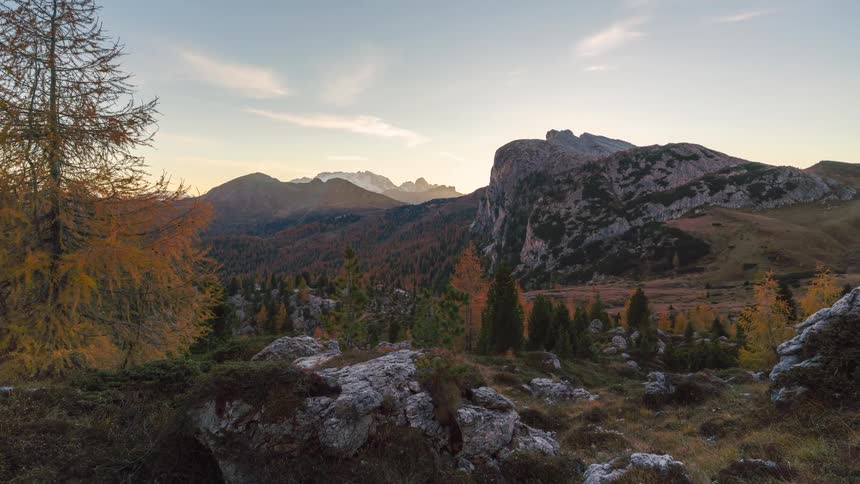 The sun shines above sharp mountain peaks in the rugged terrain