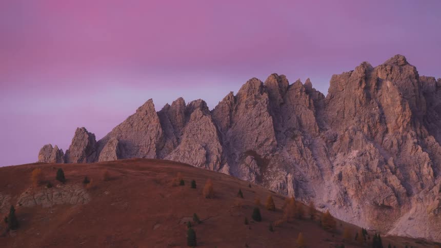 Mountain range with sharp peaks under a sky colored in shades of pink and blue at dusk