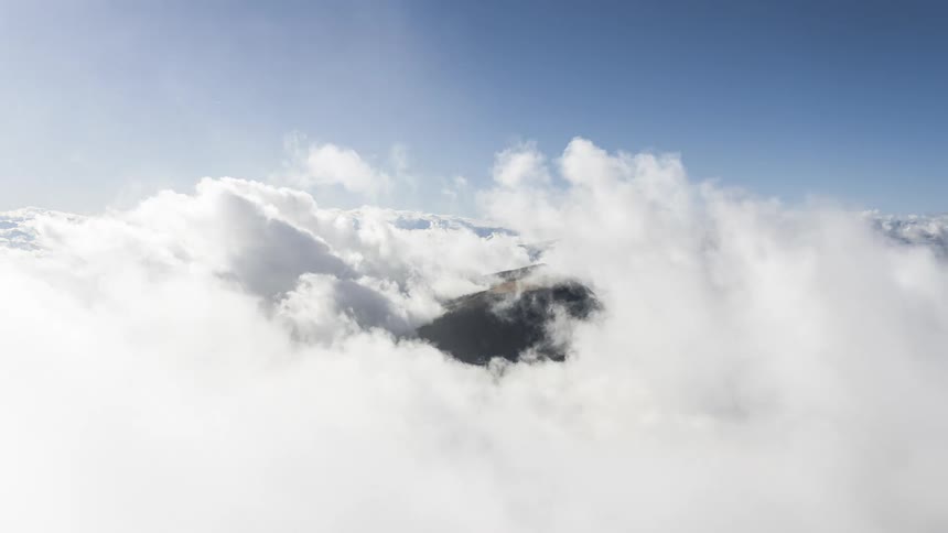 Vast expanse of white clouds under a clear blue sky above mountain peaks