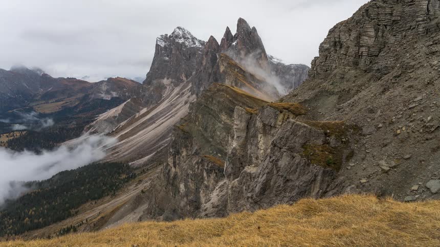 Time lapse of clouds moving around a mountain landscape with sharp jagged peaks