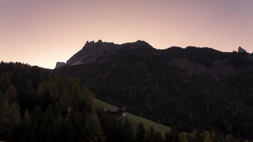 Mountainous landscape with an isolated wooden house and a dawning purple sky