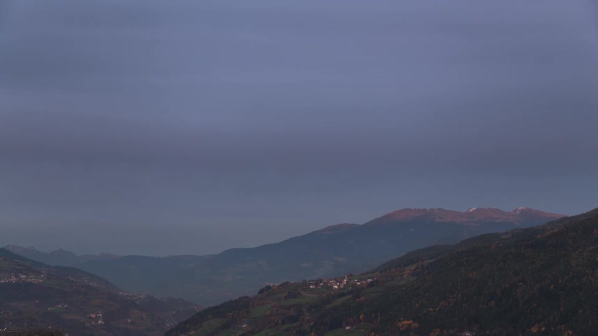 Time lapse of clouds changing color at sunset over a mountainous landscape