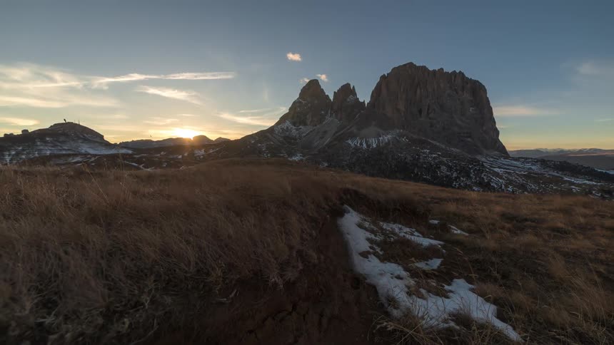 Fast moving planes travel through the sky over jagged mountain as the sun sets