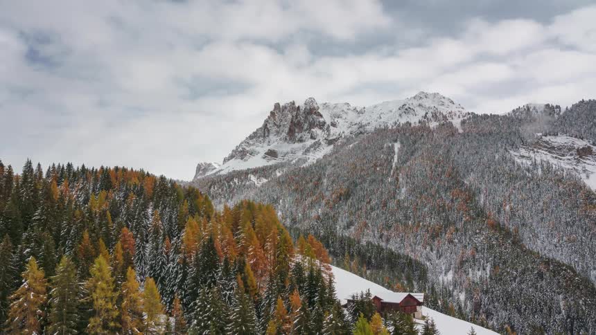 Aerial panorama of mountains with conifers covered by snow on a cloudy day