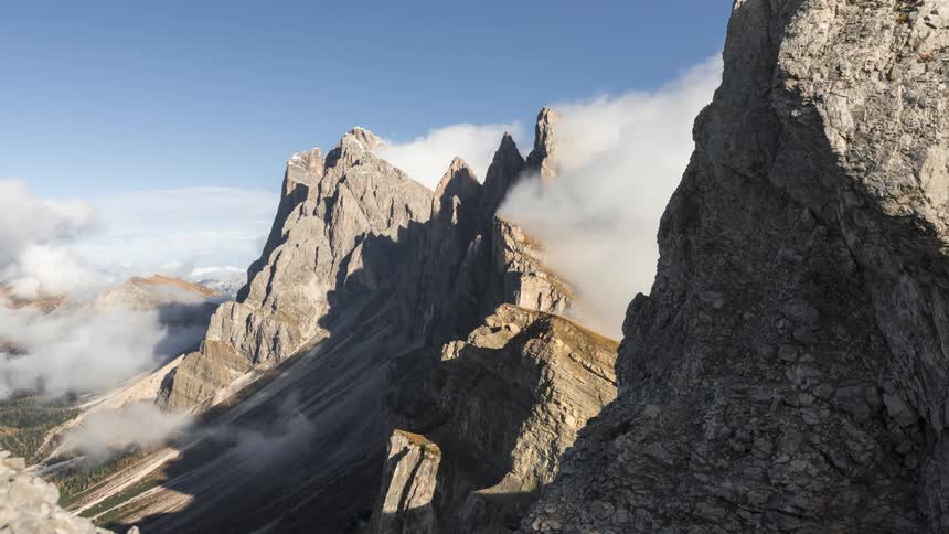 Clouds billow around a rocky mountain peak