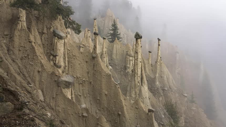 Series of tall narrow geological formations with rocks balanced on their peaks