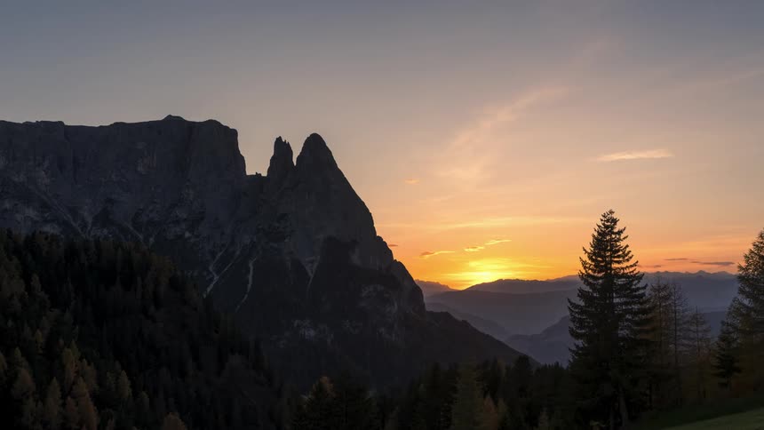 Aerial of the sun rising in the distance across the mountains