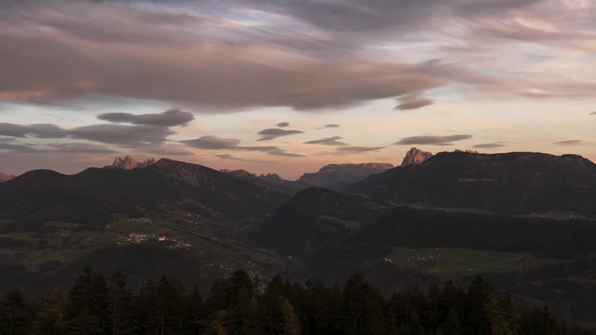 Landscape of a mountain valley with trees and vegetation against a cloudy sky at dusk