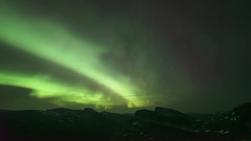 Silhouette of mountains against a sky with northern lights