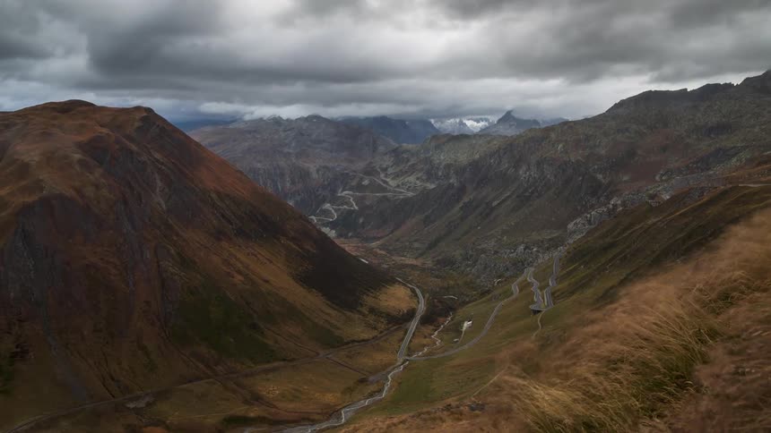 Clouds flow past mountains and a deep valley